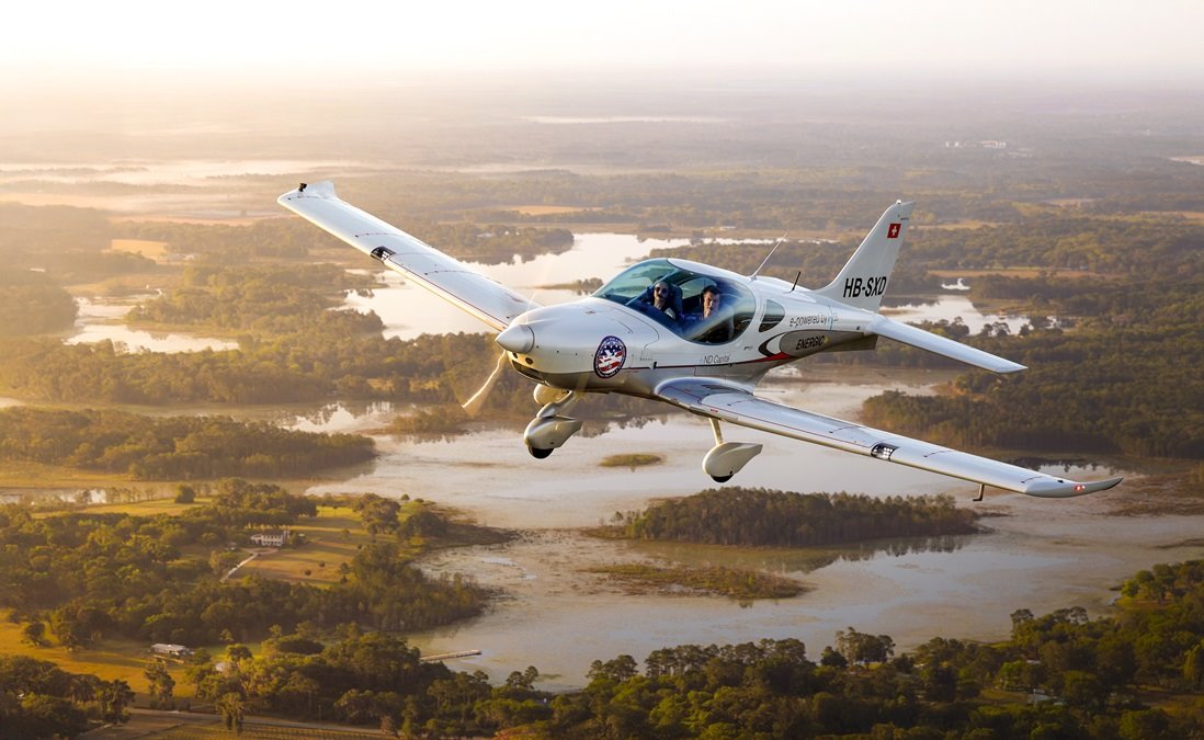 Electric light aircraft flying over a sunlit landscape